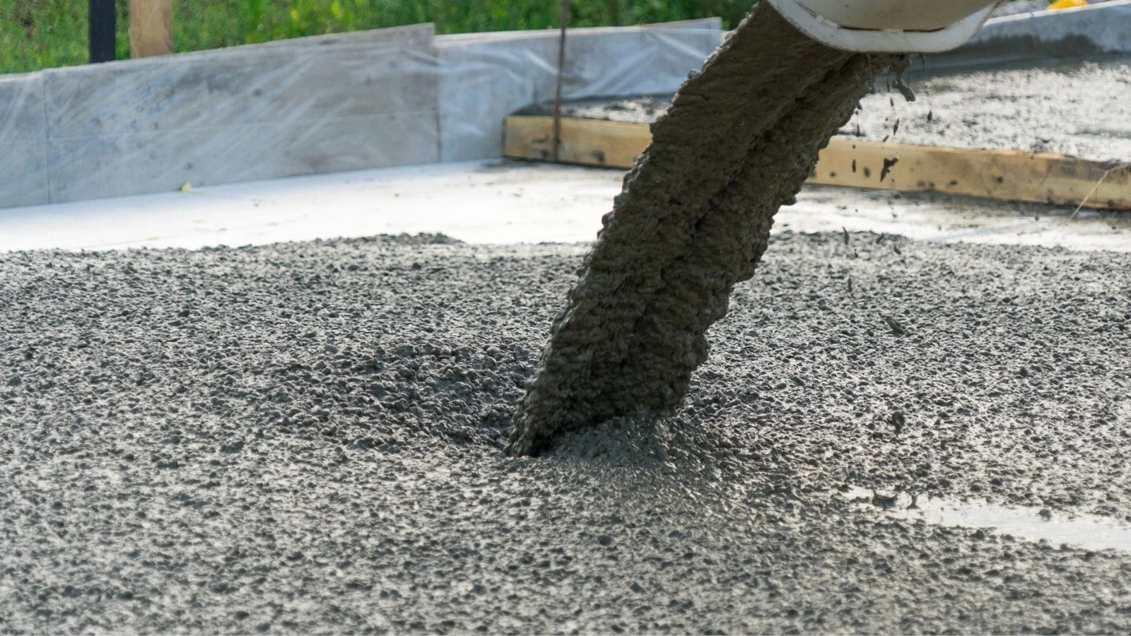 Concrete pouring into foundation with wooden forms and gravel base