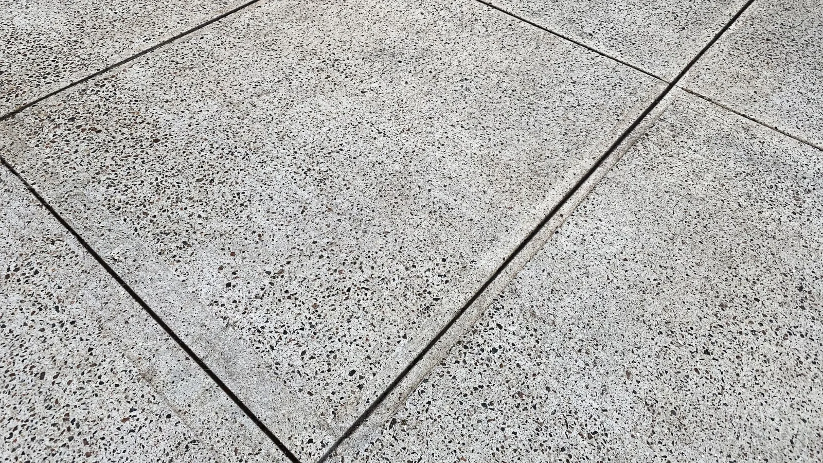 Exposed aggregate concrete patio with control joints in herringbone pattern