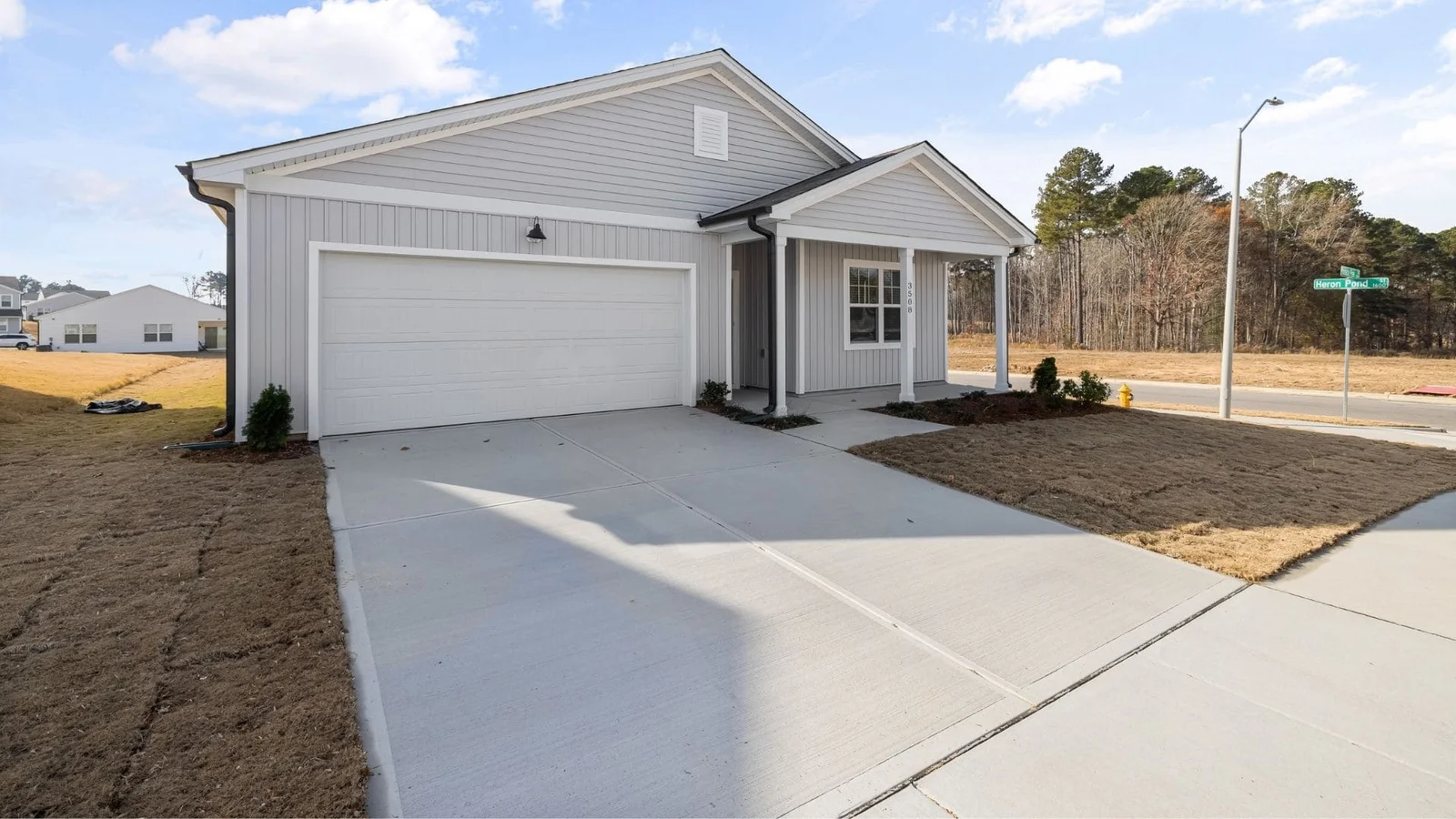 Finished concrete driveway and entryway with control joints in front of white metal-sided home