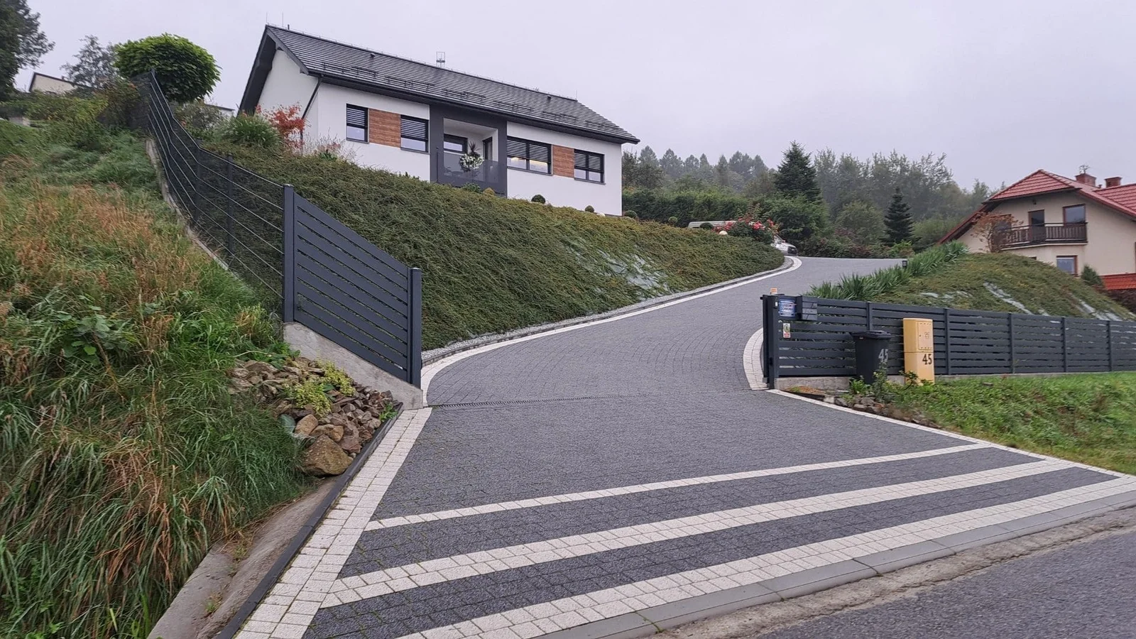 Striped concrete driveway with light and dark paving bands and edging borders