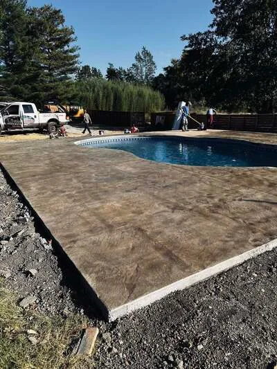 Stamped concrete pool deck with wood-grain texture pattern surrounding in-ground pool